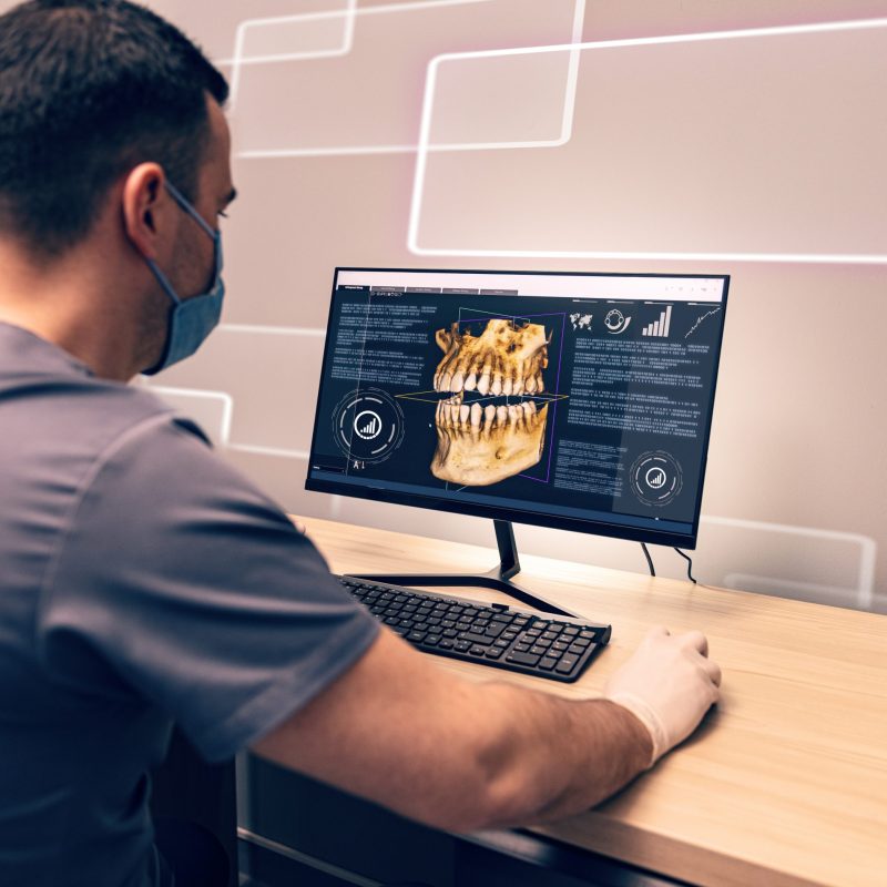 Young dentist examining an x-ray on computer in dental clinic